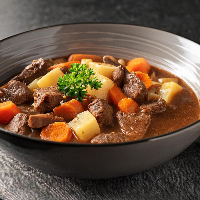 Beef stew in a white glass bowl on a black countertop 