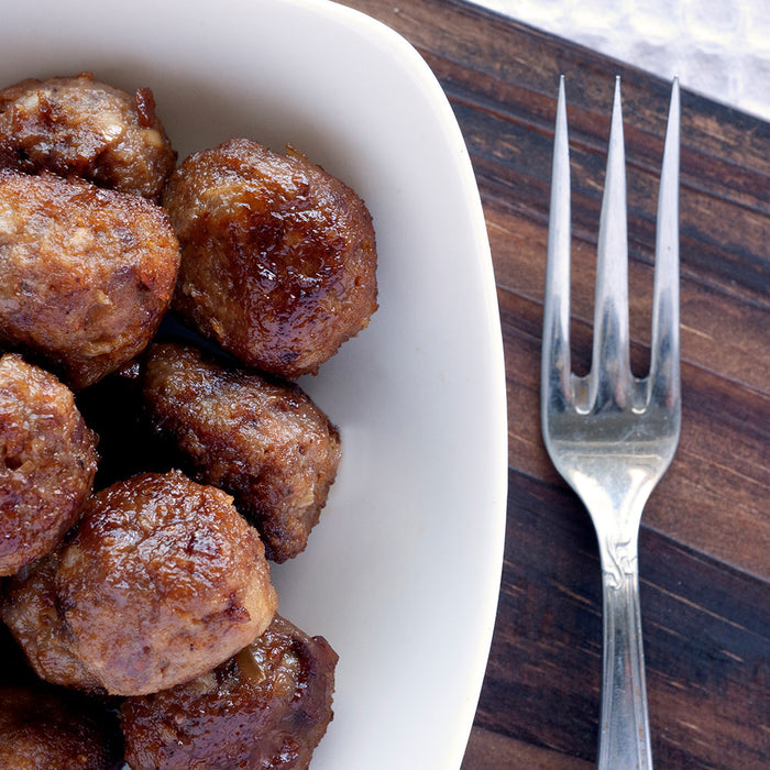 One-Pot Apple Sausage Meatballs in a white bowl on a wood counter top 