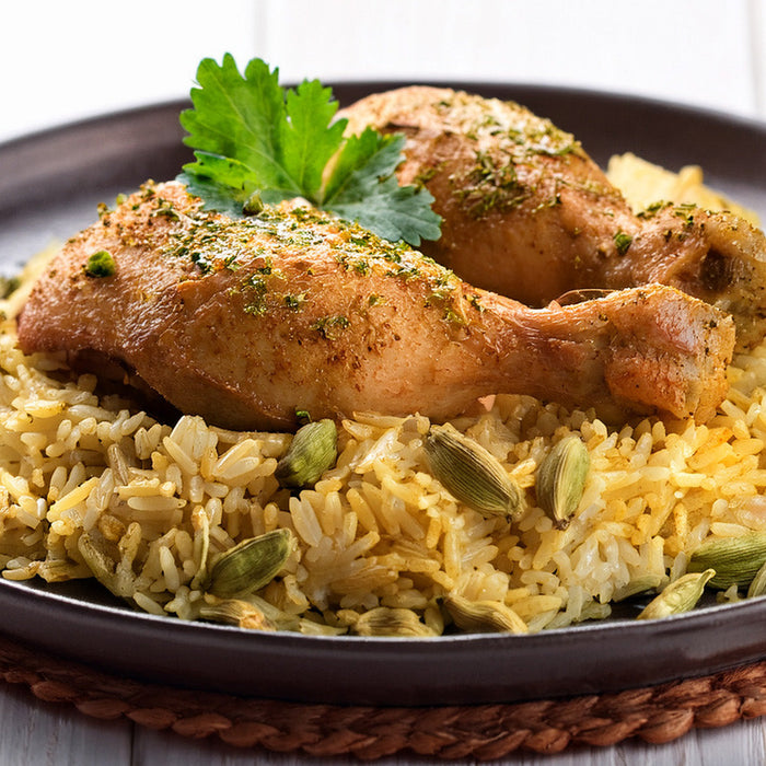 Seasoned chicken on cardamom rice on a black plate