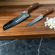 Damascus Santoku Paring Set on cutting board with wooden chopped food