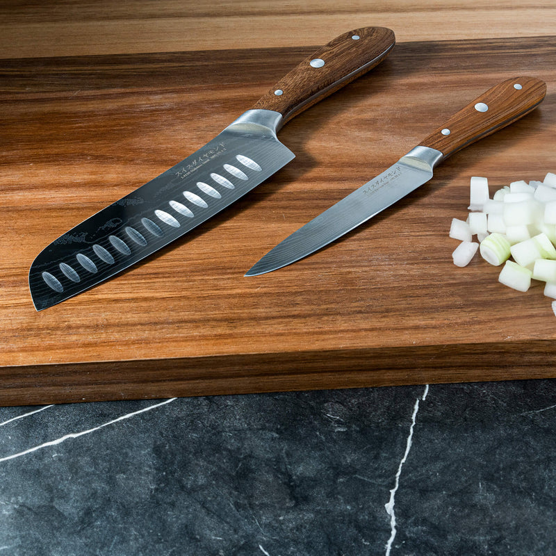 Damascus Santoku Paring Set on cutting board with wooden chopped food