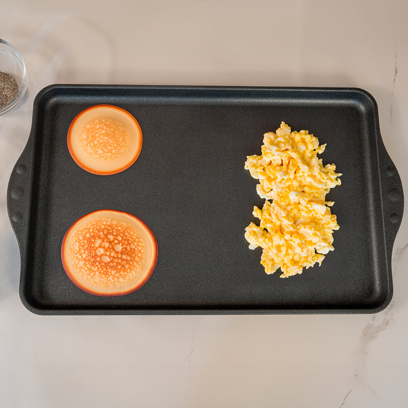 XD Nonstick 17" x 11" Double-Burner Griddle in use with pancakes and eggs on surface